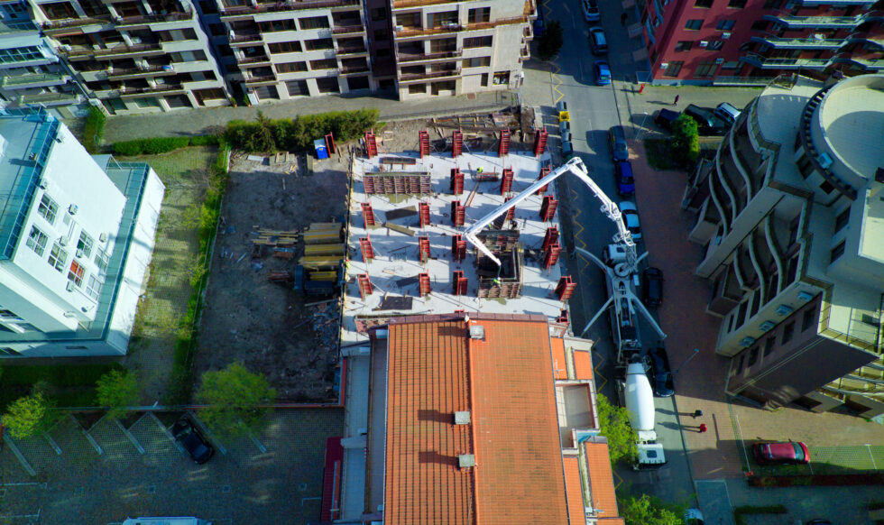 Bird's eye view of diligent construction of large multi-storey resort apartments in residential area with empty streets and trendy cars near sea sandy beach of Black Sea in town of Pomorie, Bulgaria
